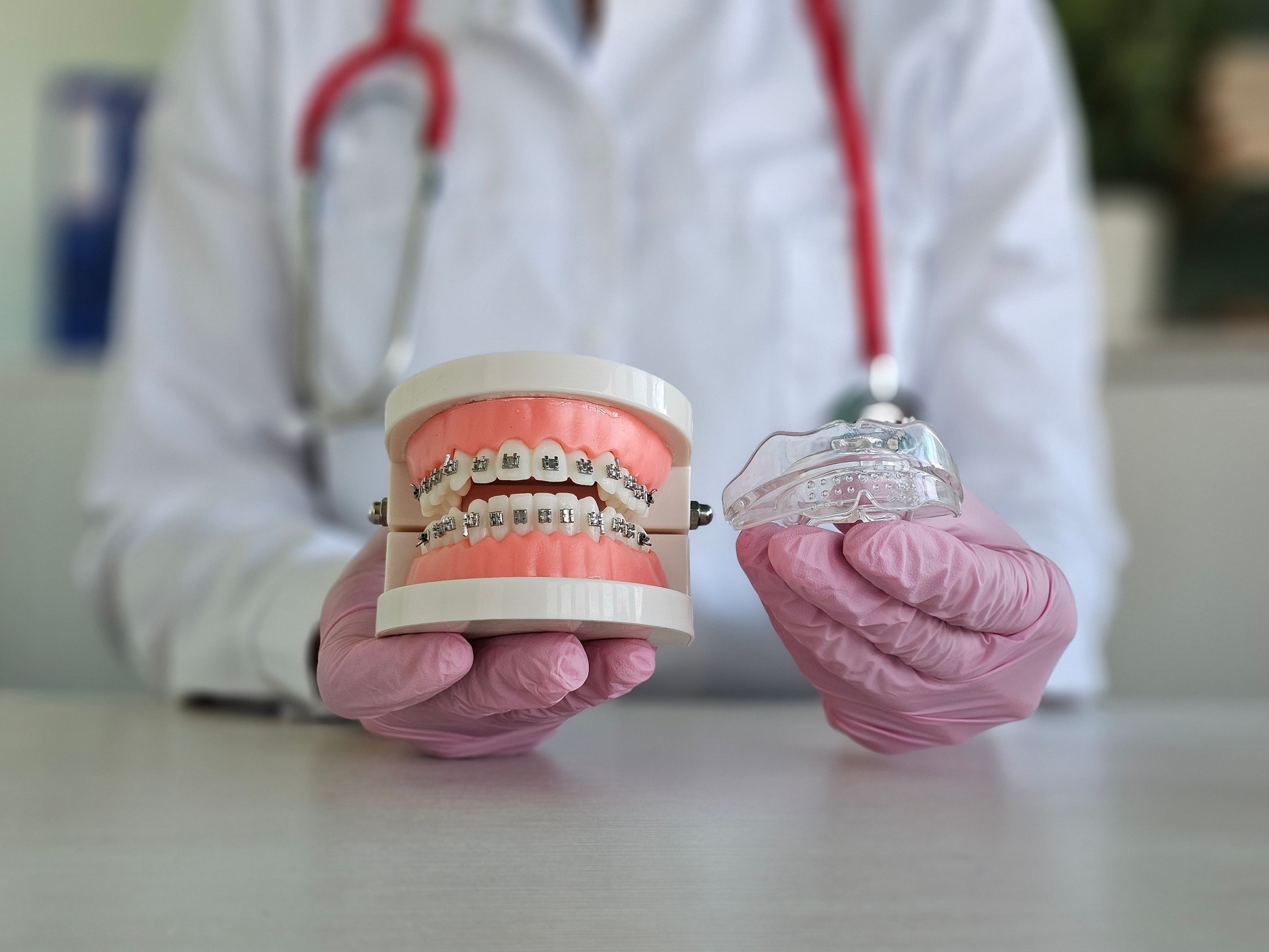Orthodontist demonstrating dental braces with a model and clear aligner during a consultation